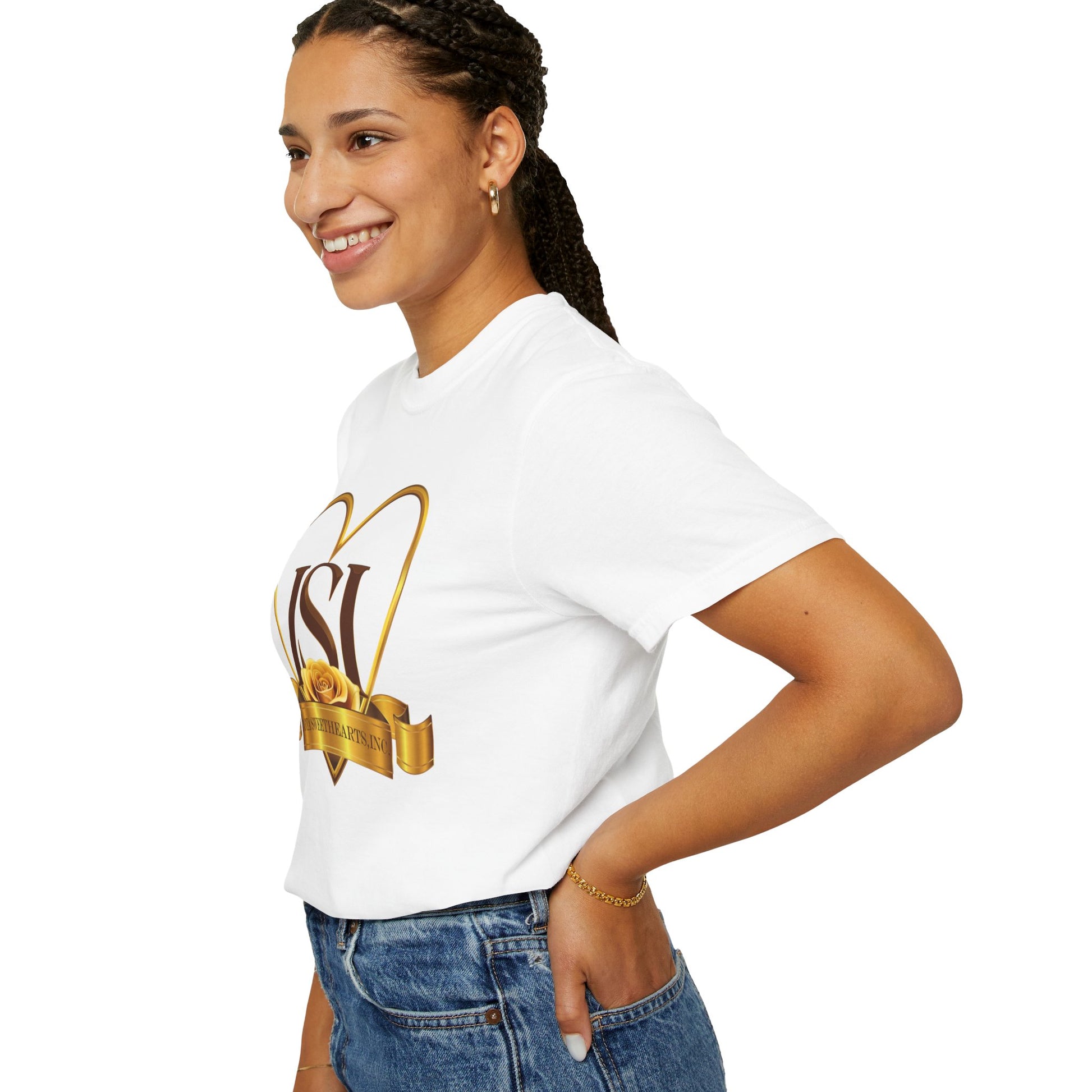 A smiling woman with braided hair is shown in a side profile, wearing a white t-shirt featuring the Iota Sweethearts, Inc. logo. The design displays large brown "ISI" letters inside a gold heart outline, with a yellow rose and gold ribbon reading "Iota Sweethearts, Inc." across the front. She has one hand in the pocket of her high-waisted blue jeans and is accessorized with hoop earrings and a gold bracelet. The background is plain white, emphasizing the clarity of the shirt's design.
